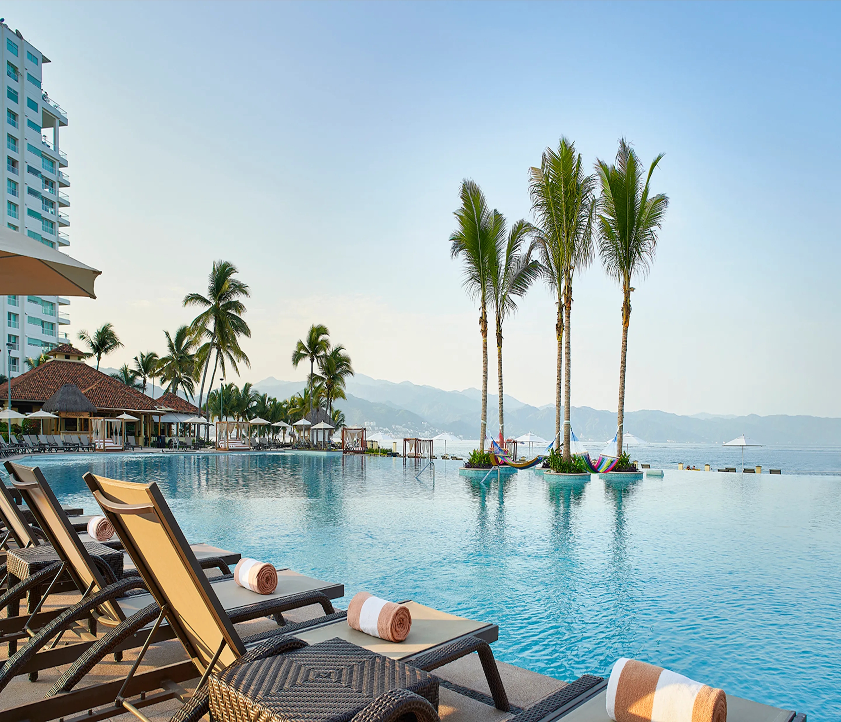 Luxury resort infinity pool with ocean view and palm trees